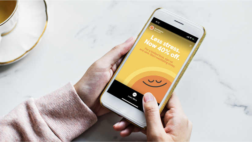 Hands holding a mobile phone showing a Headspace ad