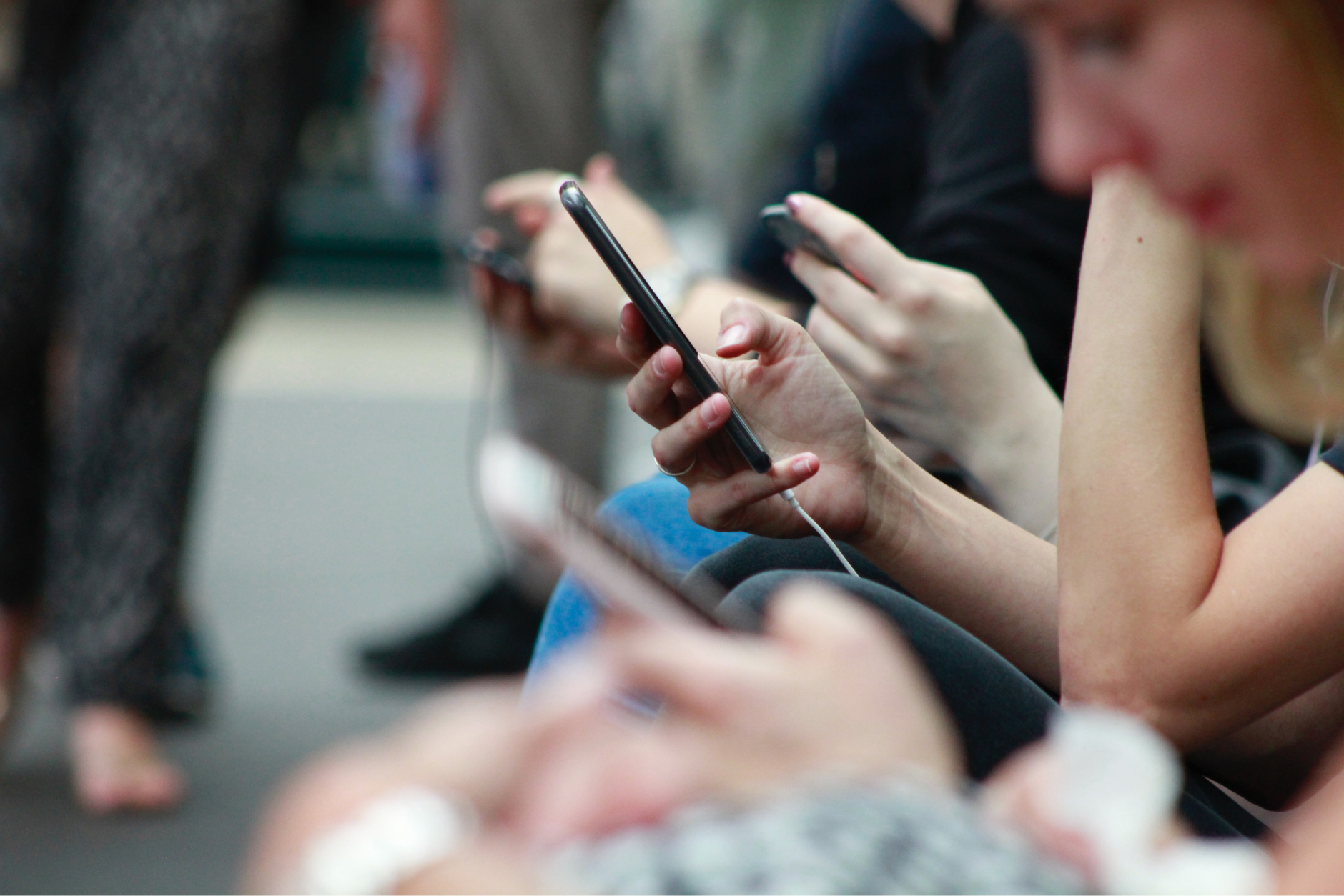 Closeup of several people's hands holding cell phones; inset of digital media dashboards